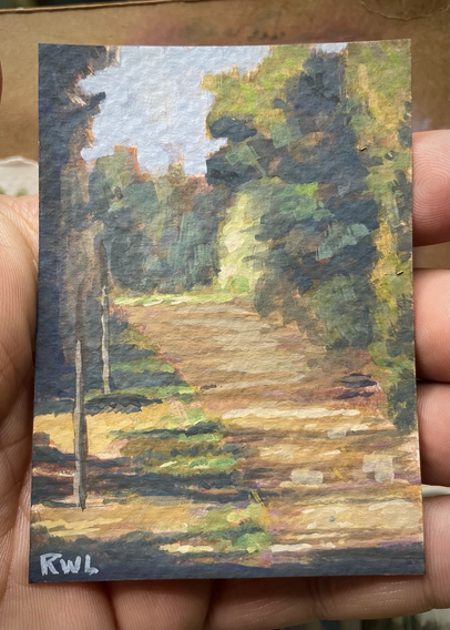 Miniature painting, held in the palm of a hand, of a dirt road between tall trees, with bright light in the foreground and shadows further away between trees.