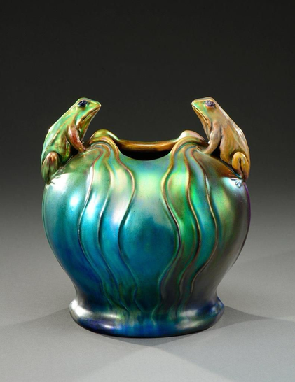 “A rounded vase on a circular heel in iridescent enameled ceramic representing two frogs in relief facing each other on a wavy background imitating water. Signed with the five churches stamp.”