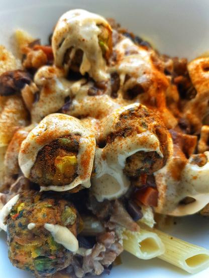 A bowl of Penne Pasta topped w/ yeast flakes; Black Bean, Aubergine & Cauliflower chilli; 'IKEA' Huvudroll vegetable balls. Topped 'Taco Truck' w/ Cheezy Sauce; Wasabi Mayo; Smoked Paprika.