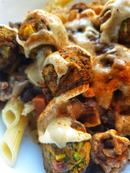 A bowl of Penne Pasta topped w/ yeast flakes; Black Bean, Aubergine & Cauliflower chilli; 'IKEA' Huvudroll vegetable balls. Topped 'Taco Truck' w/ Cheezy Sauce; Wasabi Mayo; Smoked Paprika.