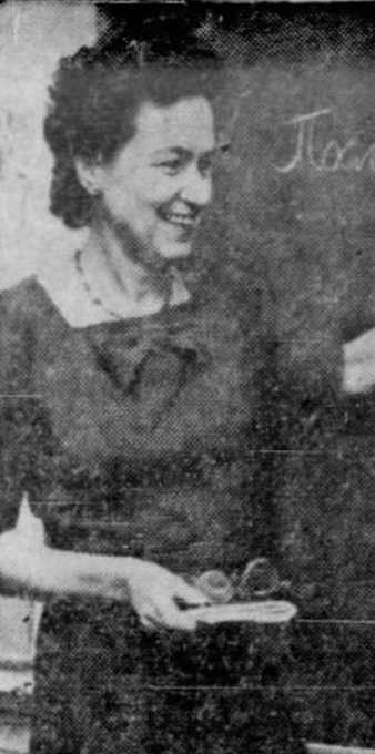 Ludmilla Turkevich, smiling and standing at a blackboard; from a 1961 newspaper