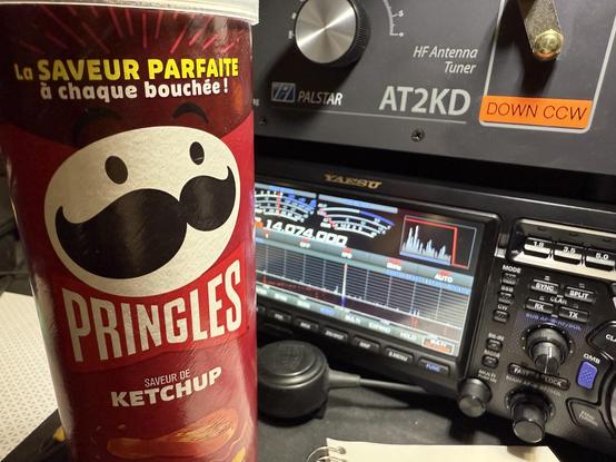 A can of Pringles ketchup flavor labeled in French sits in front of a ham radio.