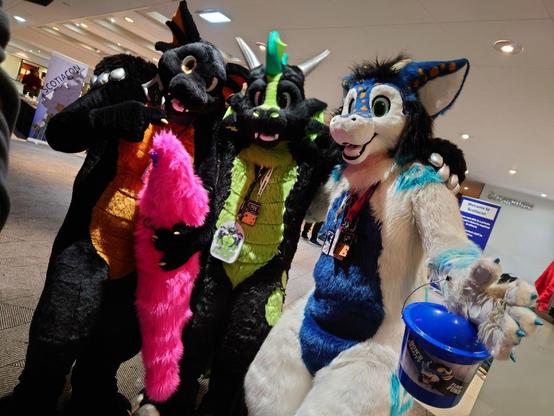 3 dragon fursuitera. A black and copper, a black and green, and a white and black