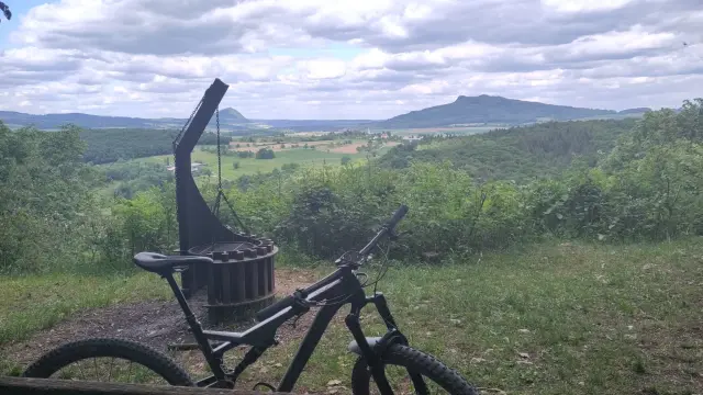 Ein Mountainbike lehnt an einer Sitzbank. Im Hintergrund ist eine Grillstelle und der Ausblick in die Hegaulandschaft.