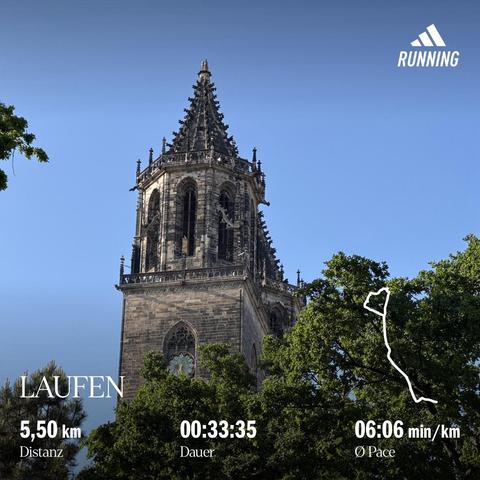 Spitzen der Domtürme des Magdeburger Doms (Südturm) vor blauen Himmel, schräg von unten aufgenommen, im Vordergrund Bäume mit grünen Blättern