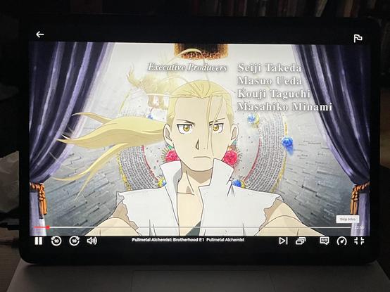 Picture of a tablet screen running the opening of the anime Fullmetal Alchemist Brotherhood. The screenshot features a close-up portrait of the protagonist of the anime Edward Elric