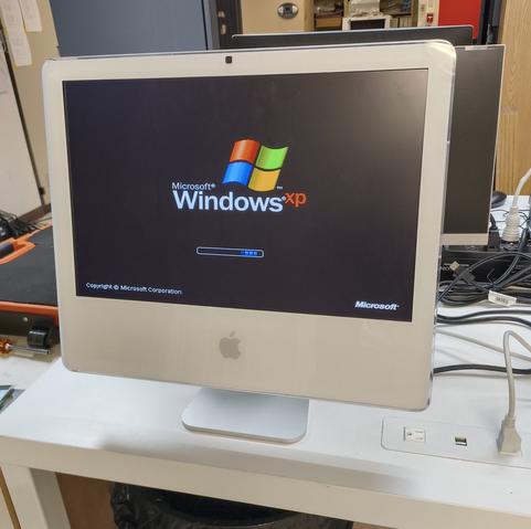 Showing a picture of a white polycarbonate iMac computer circa 2006 booting into Windows XP.