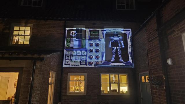 A screen from Speedball 2 projected on to the side of a house.