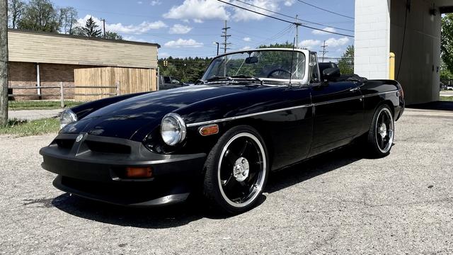 Photograph of a black rubber-bumper MGB from the front left on a sunny day.
