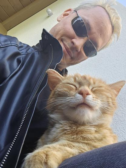 Photo of a super relaxed cat on my lap and me looking a bit derpy but cool thanks to the shades I'm wearing.