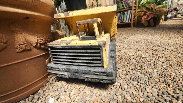 color photo of a rusty yellow Tonka dump truck - front angle