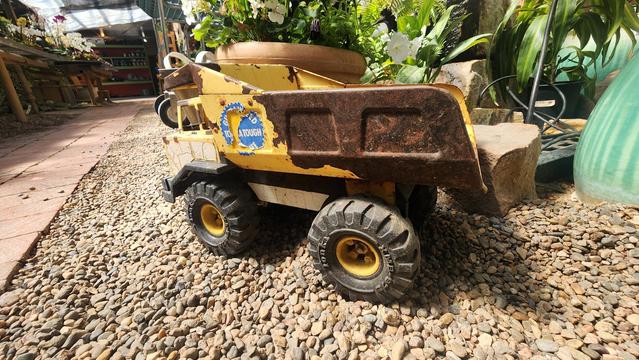 color photo of a rusty yellow Tonka dump truck - side angle