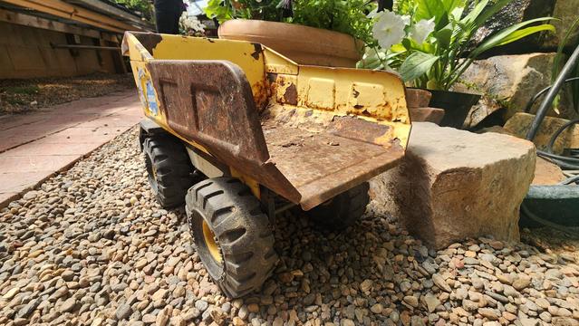 color photo of a rusty yellow Tonka dump truck - rear angle
