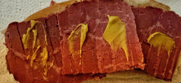 Sliced corned beef leftovers with hot English mustard on hot dog rolls.