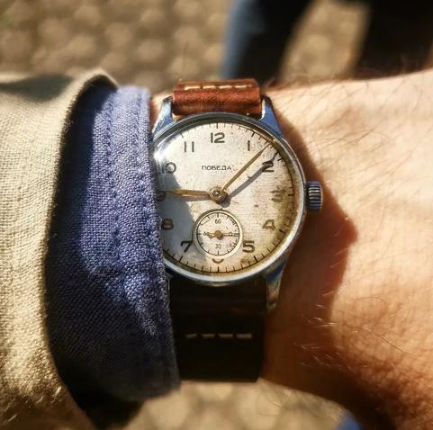 foto dell'orologio indossato da me al polso.
cinturino in pelle marrone con cuciture a vista, quadrante bianco molto usurato, lancette e numeri dorati. come da moda degli anni 50 è molto piccolo (32mm)