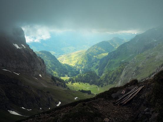 Mountain landscape in the Swiss Alps. Sunlight streams through a gap in the clouds into the green valley. Landscape photography by Marco Zedler