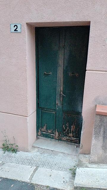 Una porta di legno, erosa dai tarli, portata da una casa di Monreale ad una casa di Campofelice di Roccella in Sicilia nel 1889 e ancora oggi presente nel fare il proprio uso.