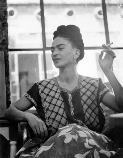 SW Fotografie
Frida Kahlo sitzt mit dem Rücken zu einem Fenster.
In ihrer linken Hand hält sie eine Zigarette