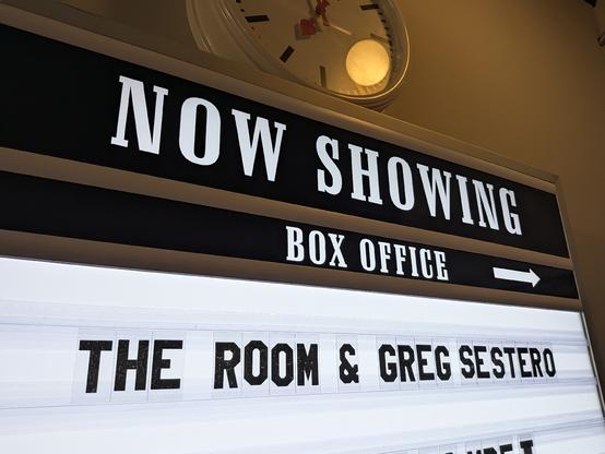 A cinema "Now Showing" sign which reads "The Room & Greg Sestero"