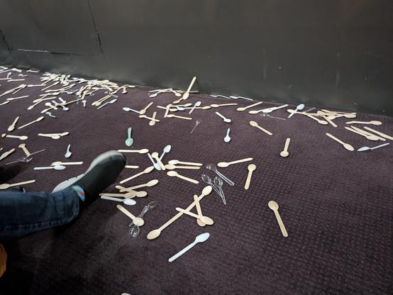The floor of the cinema after the screening had ended. It is covered in all wooden and plastic spoons that had been thrown throughout the film.