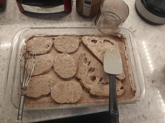 6 slices of small round bread and two large slices of triangular bread sitting in custard mixture