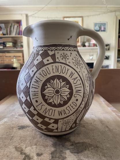 Photo of unfitted clay jug decorated with plant and abstract patterns using sgraffito.