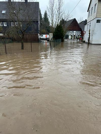 Überflutete Strasse in einem Ort. Auch an den Häusern im Hintergrund steht das Wasser an den Wänden.