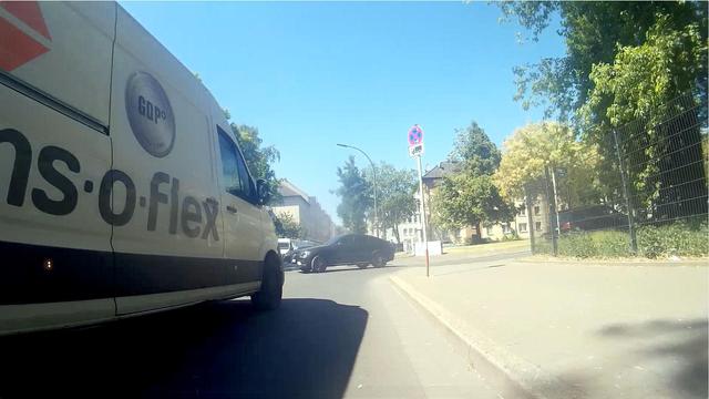 Image of a dashcam on a bicycle just before a junction. The bicycle is being overtaken very closely by a van and the vehicle is in the process of blocking the bicycle's lane