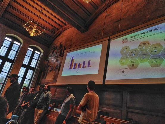 A group of people stands in front of a presentation display in the chamber of Town Hall.