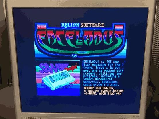 Photograph of a flatscreen monitor displaying a multi-coloured advert for Enceladus disk magazine. The image uses more than the maximum 16 colours allowed in a SAM Coupé screen by doing line-interrupt palette changes. The display is being generated by a ZX Spectrum Next (out of shot).