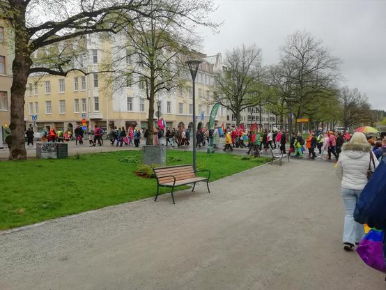 Kulkue kääntyy kaupungintalon puistosta Rautatienkadulle. Ihmisiä on paljon. Puut vihertävät.