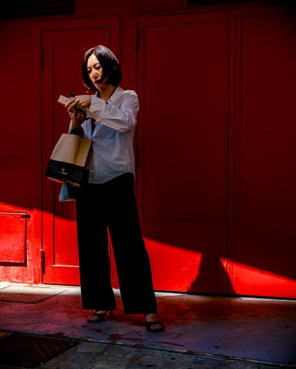 Woman standing in front of a red wall, eating sushis