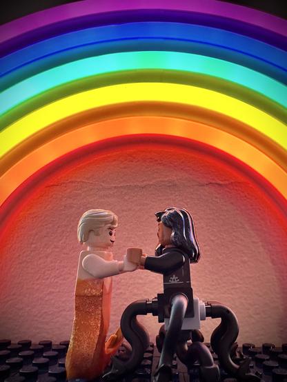 Lego MerStede and Lego MerKraken Ed holding hands under a glowing rainbow