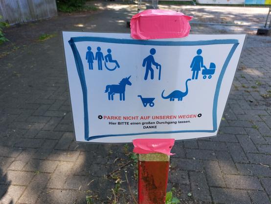 Ein "parke nicht auf unseren Wegen" Schild
Mit Mann, Frau, Rollstuhlfahrenden, Mann am Stock, Frau mit Kinderwagen, Einhorn, Schubkarre und Dinosaurier