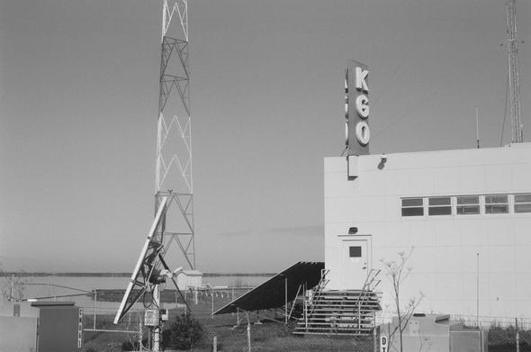 A radio tower points skyward next to an abandoned radio station in the salt flats of the southern Bay Area.