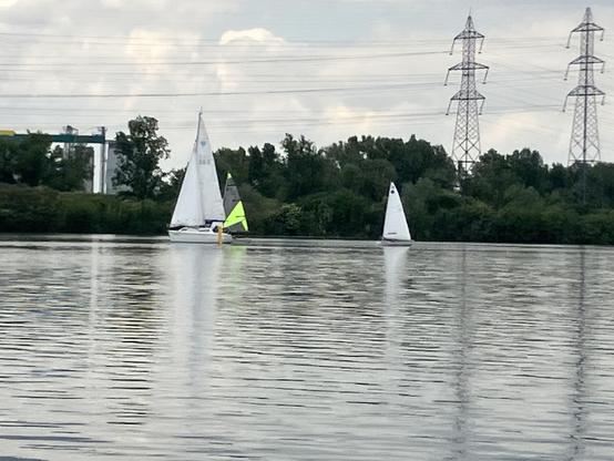 Segelboote auf dem Wasser. Zwei kleine Sporboote, ein Drittes größer.