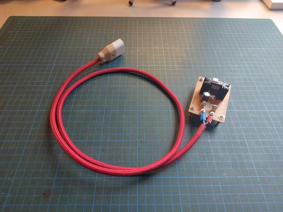 Photo of a small home made single sides PCB sitting on 4 standoffs. It's got a long cable attached using some screw lugs which terminates in a 3D printed plug
