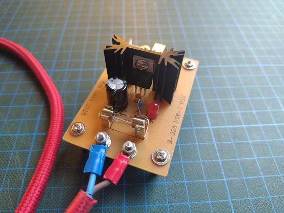 A closeup of the PCB, showing the screw lugs which attach the cable, the fuse holder, LED with resistor, capacitor and voltage regulator with a heat sink.