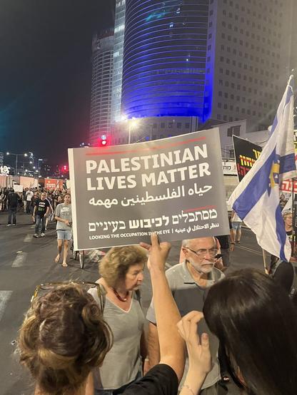 Israeli protestors march holding signs