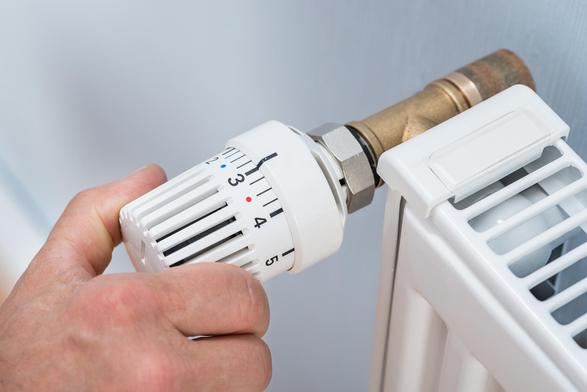 Close-up Of A Person's Hand Adjusting Temperature Of Radiator Thermostat