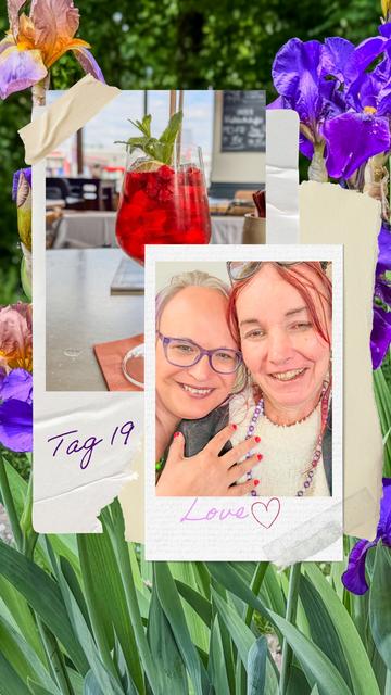 Collage mit sommerlich-blumigem Hintergrund aus lilafarbenen und orange-gelben Schwertlilien. Oben links ein erfrischendes Himbeer-Minz-Getränk (Virgin Wildberry) im Glas auf einem Terrassentisch, darunter der handschriftliche Schriftzug „Tag 19“. Im Vordergrund ein fröhliches Selfie von zwei Frauen, die eng aneinander lächeln. Eine trägt eine lila Brille, die andere hat rot gefärbte Haare. Beide wirken gelöst und verbunden, eine Hand liegt liebevoll auf der Schulter der anderen. Darunter steht in rosa Schrift „Love“ mit einem gezeichneten Herz. Die Collage strahlt Wärme, Nähe und ein Gefühl von Leichtigkeit aus.