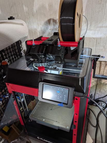 Cuboid 3D printer with an additional contraption on top of it. It is a device that takes two filament spools and merges them into a single path, with the aim of enabling seamless spool changes.