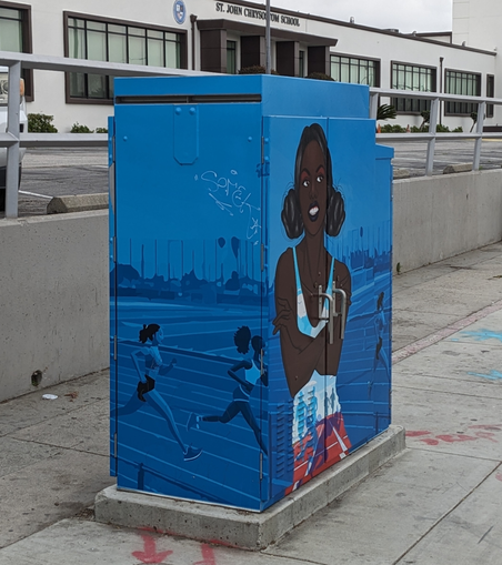 utility box with a young girl in running clothes with a track meet behind her like a glimpse of the future