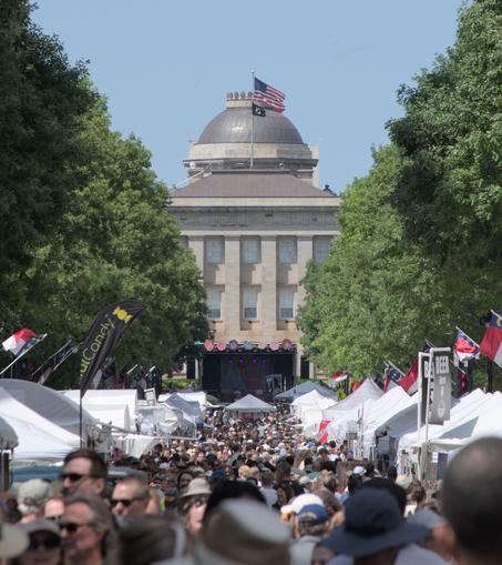 A close up view of the state capitol building, still showing the packed street leading up to it. It's a bright sunny day with blue sky and green trees line the street.