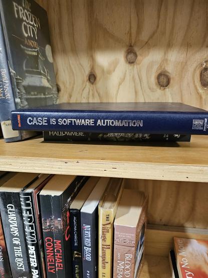 A book lying on its side in a wooden book shelf titled CASE is software automation. CASE is to software development as CAD is to hardware development.