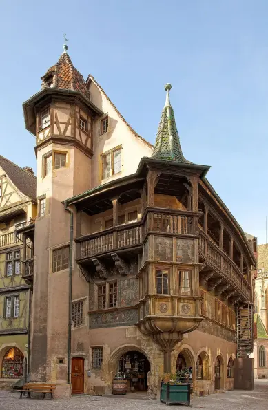 The image shows a historic building with unique architectural features, including a pointed roof, wooden balconies, and decorative elements. The structure appears to be part of a charming town, likely in Europe, characterized by medieval-style construction and colorful facades. The building has a tower-like structure, adding to its distinctive appearance. If you need more specific information or context, feel free to ask!

Image Credits: Wikimedia / Eric Gaba (Sting - fr:Sting) / CC BY-SA 3.0