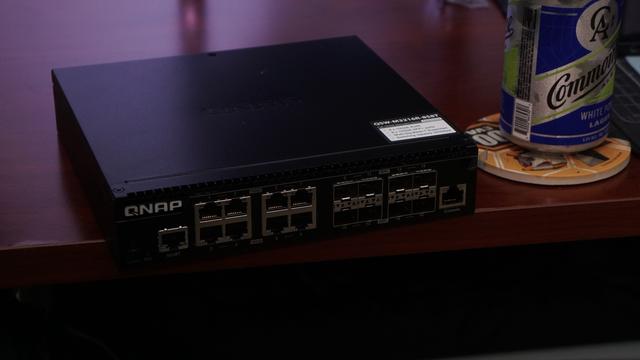 The QNAP QSW-M3216R-8S8T 10GbE port switch sitting next to a canned beer for size.  It has 8 copper 10GbE ports and 8 SFP+ ports along with console and MGMT ports.