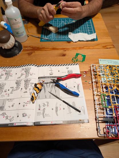 Pic of a table with various tools and things being built, one is a gunpla.