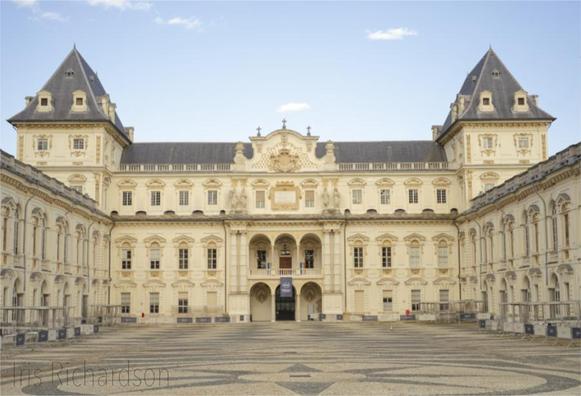 Castello del Valentino Turin - The castle is a historic building in the Italian city of Turin. It is a beautiful late afternoon in May. Small white clouds are in the blue sky, contrasting with the warm yellow color of the castle.