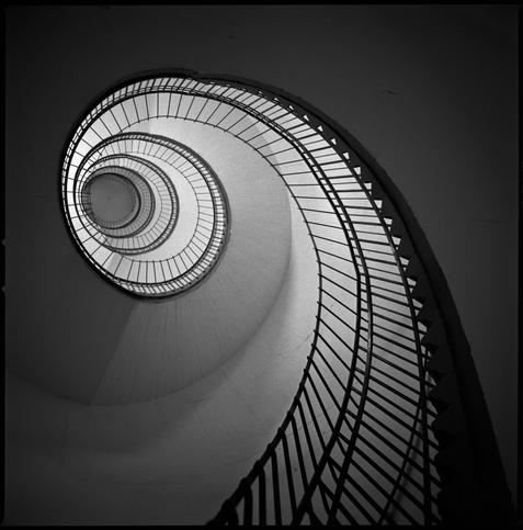 black and white photograph looking up an uneven spiral staircase inside one of the corner towers of Flakturm IV on Heiligengeistfeld in St. Pauli, Hamburg.